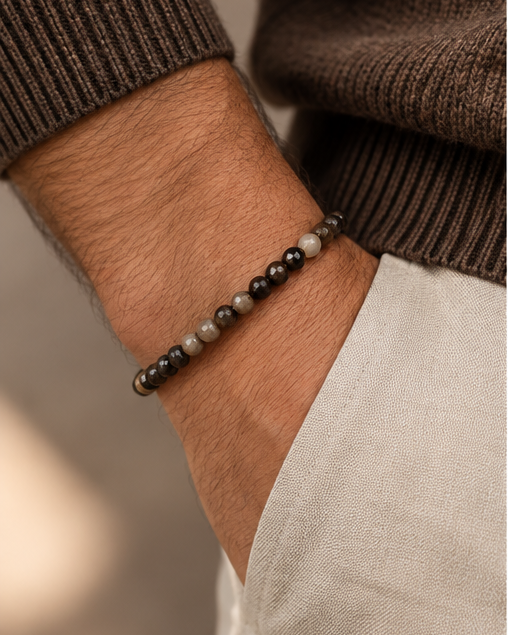 Pulseira masculina ATLAS com pequenas contas de pedras naturais facetadas no pulso de um homem com malha castanha