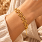 Close-up da pulseira LIRIA dourada com flores no pulso