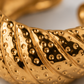 Macro da textura em relevo do anel NERA dourado em aço inoxidável