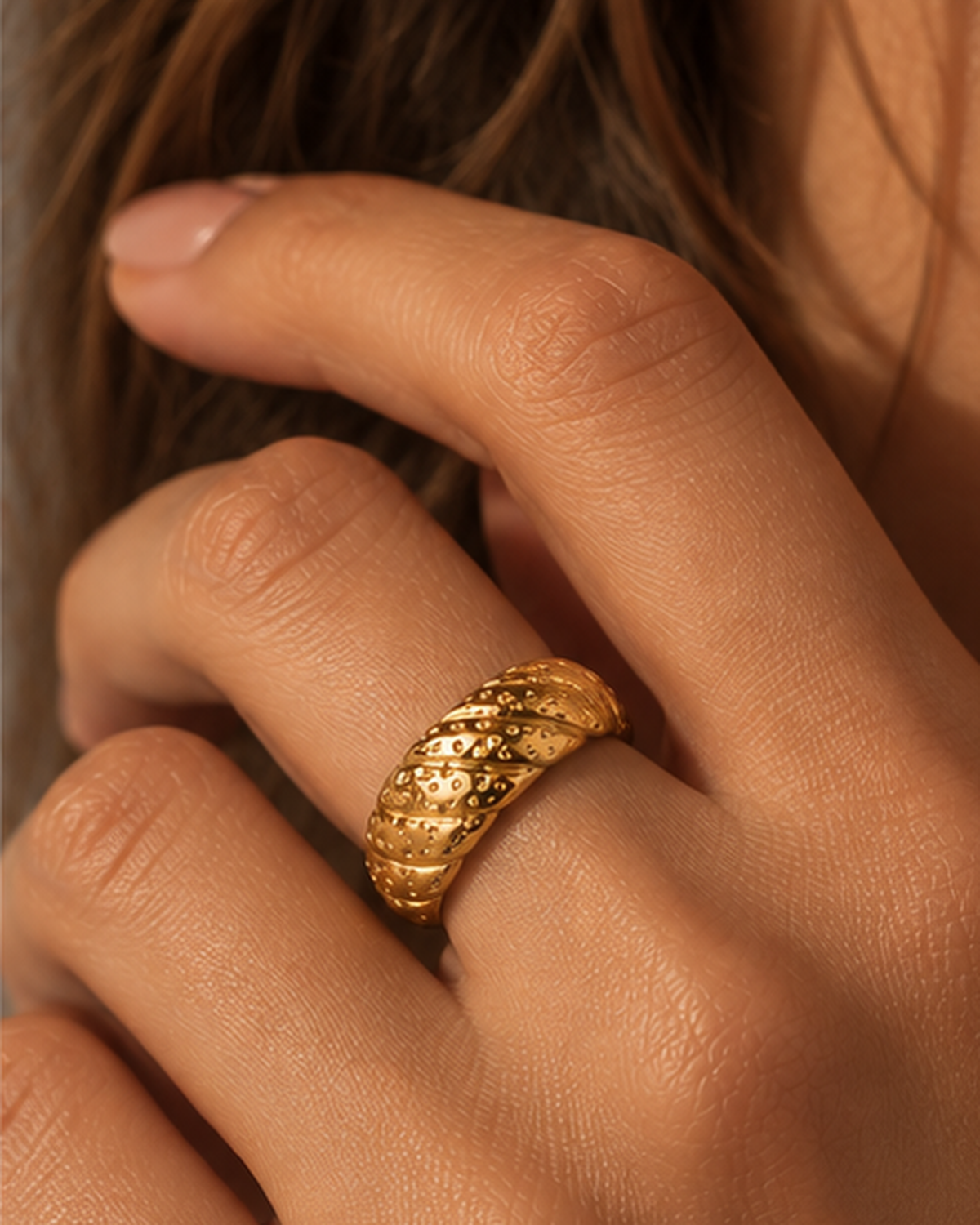 Anel NERA dourado em aço inoxidável no dedo de uma modelo, em escala realista