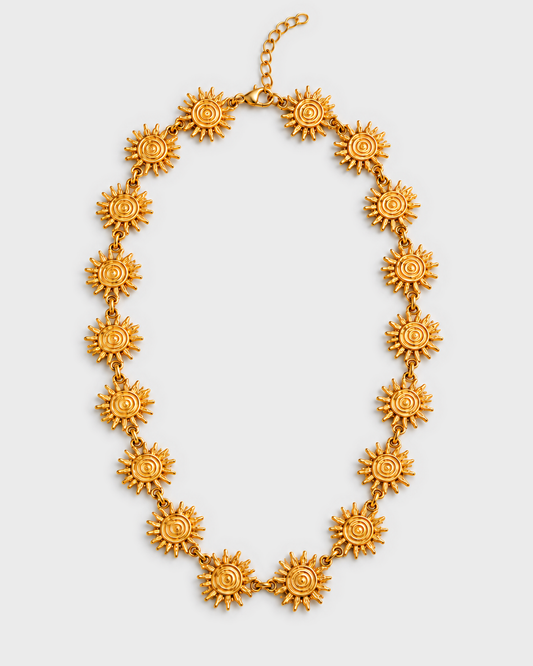 Colar SOLEA dourado com elementos em forma de sol, imagem integral com fecho e extensor para cima, fundo cinzento #EBEBEB