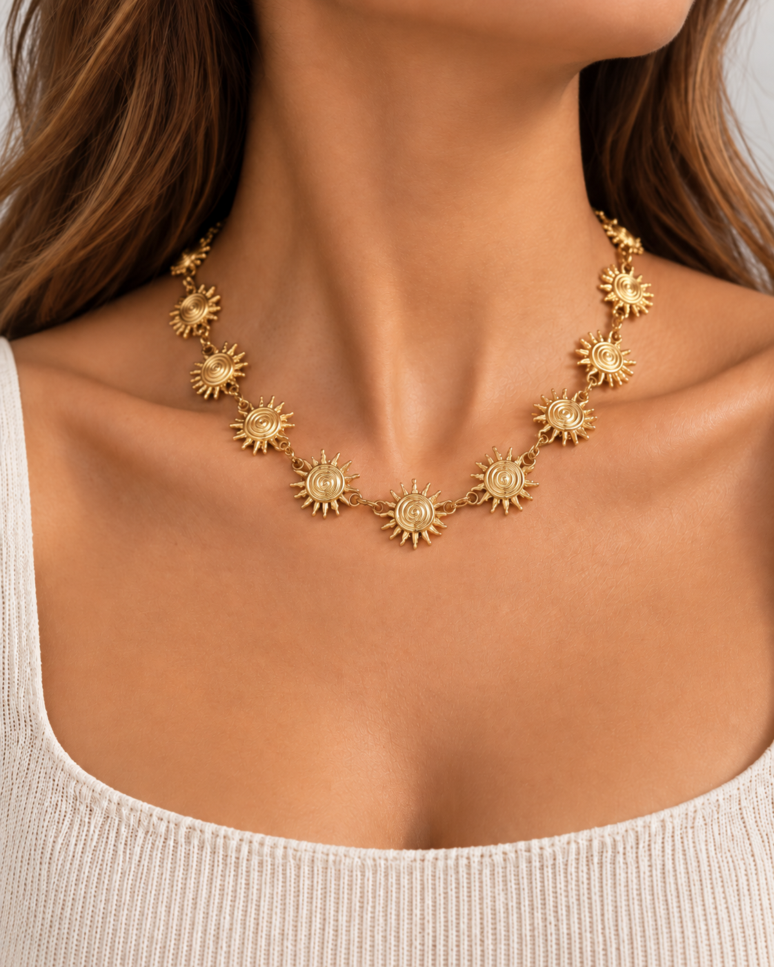 Colar SOLEA dourado com sóis usado ao pescoço por modelo, enquadramento das clavículas sem mostrar o rosto
