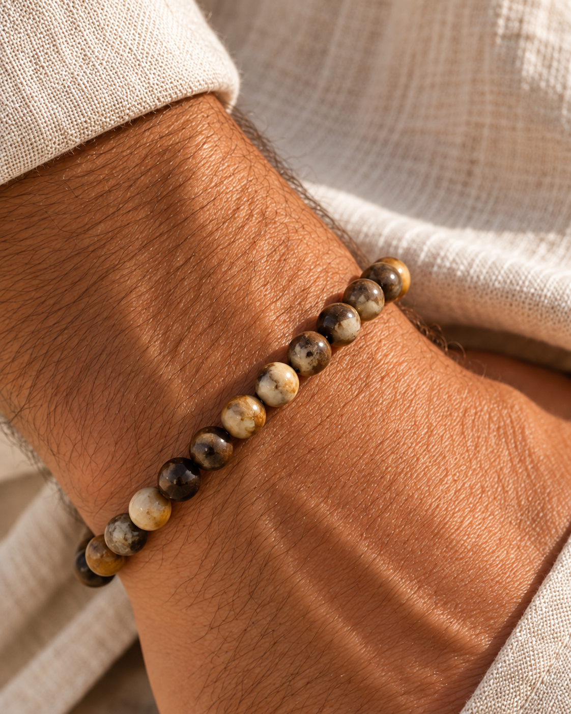 Pulseira masculina TERRA em pedras naturais no pulso de homem com camisa de linho bege